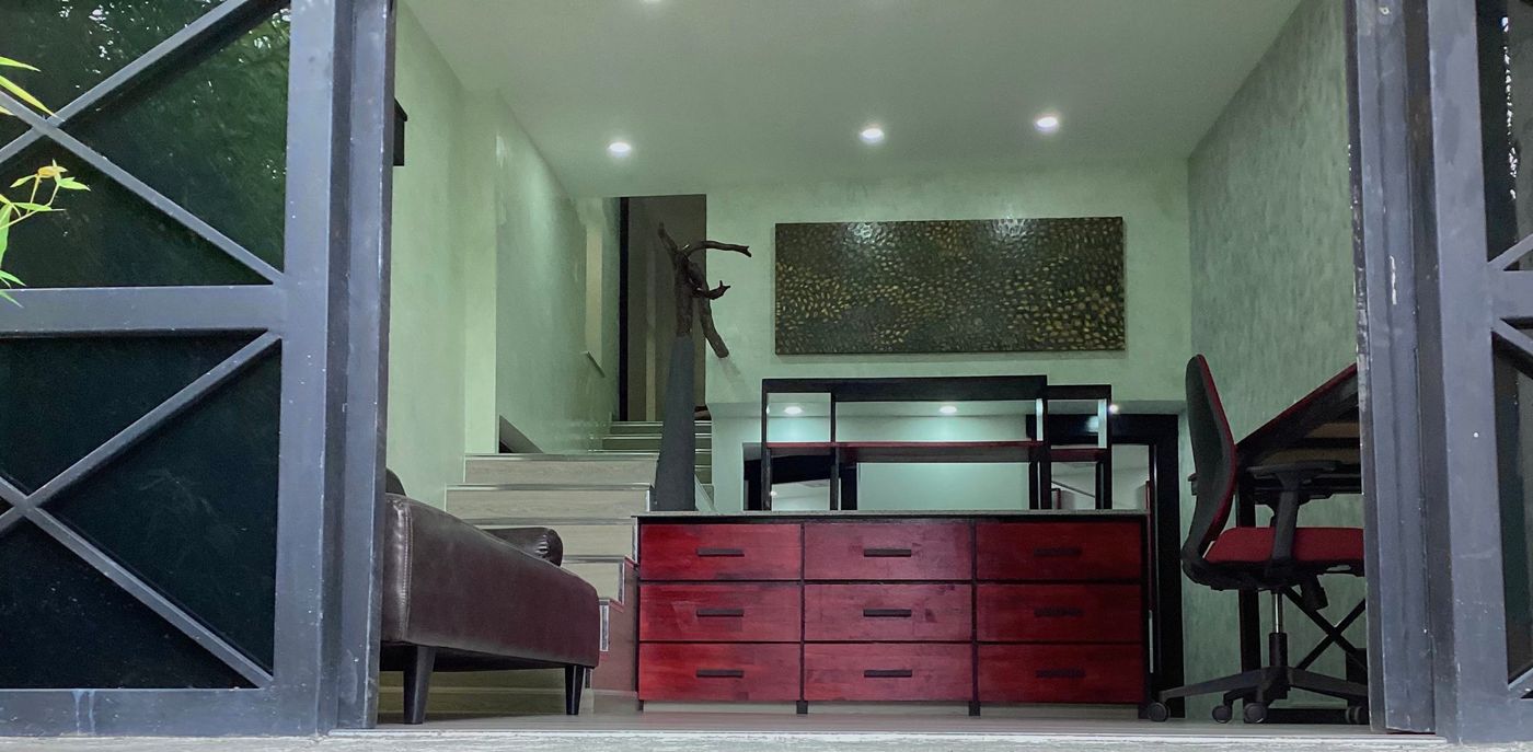 Interior de la cabaña con escalones, cómoda roja y ventanales